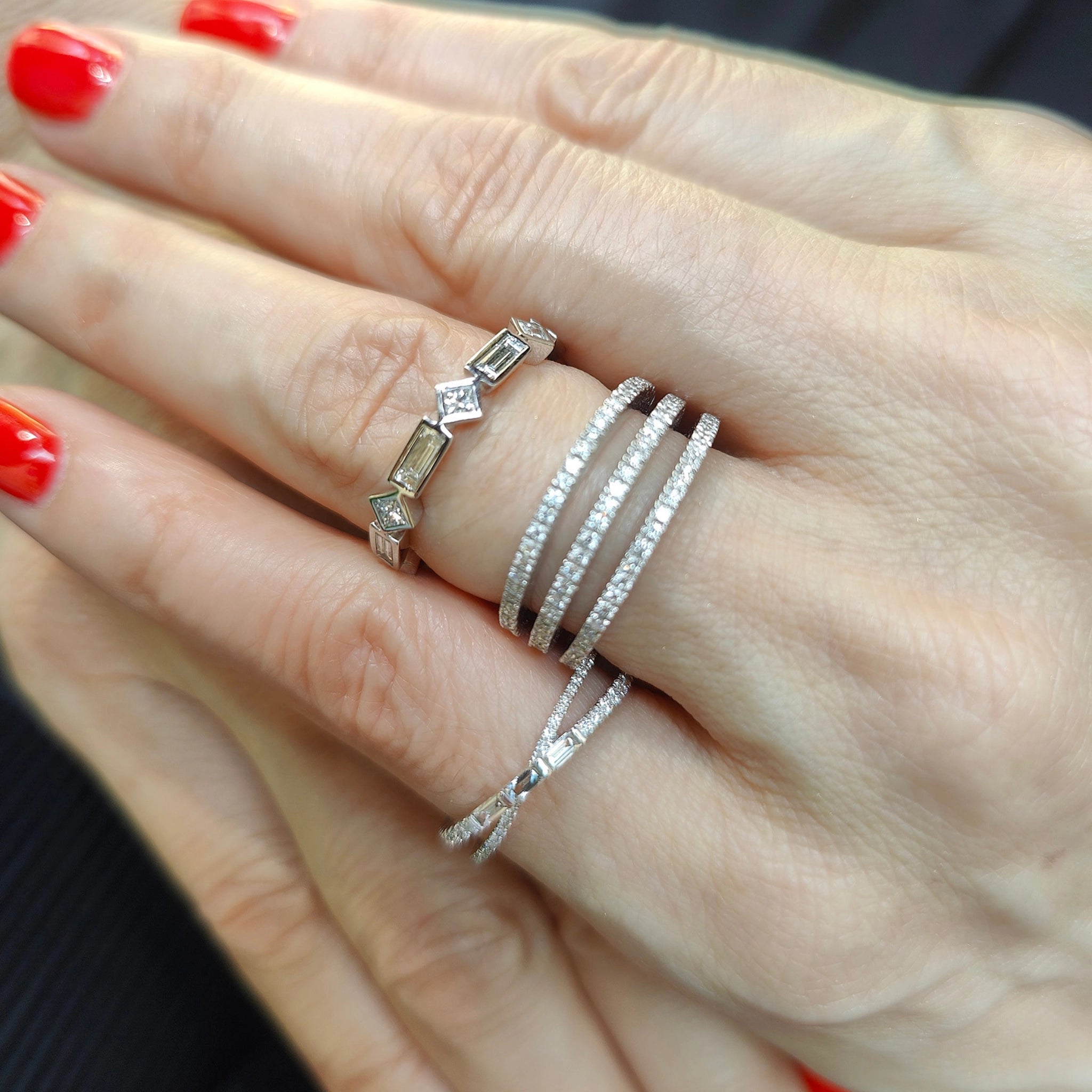 Elegant hands adorned with multiple stylish diamond rings showcasing sparkle and sophistication.