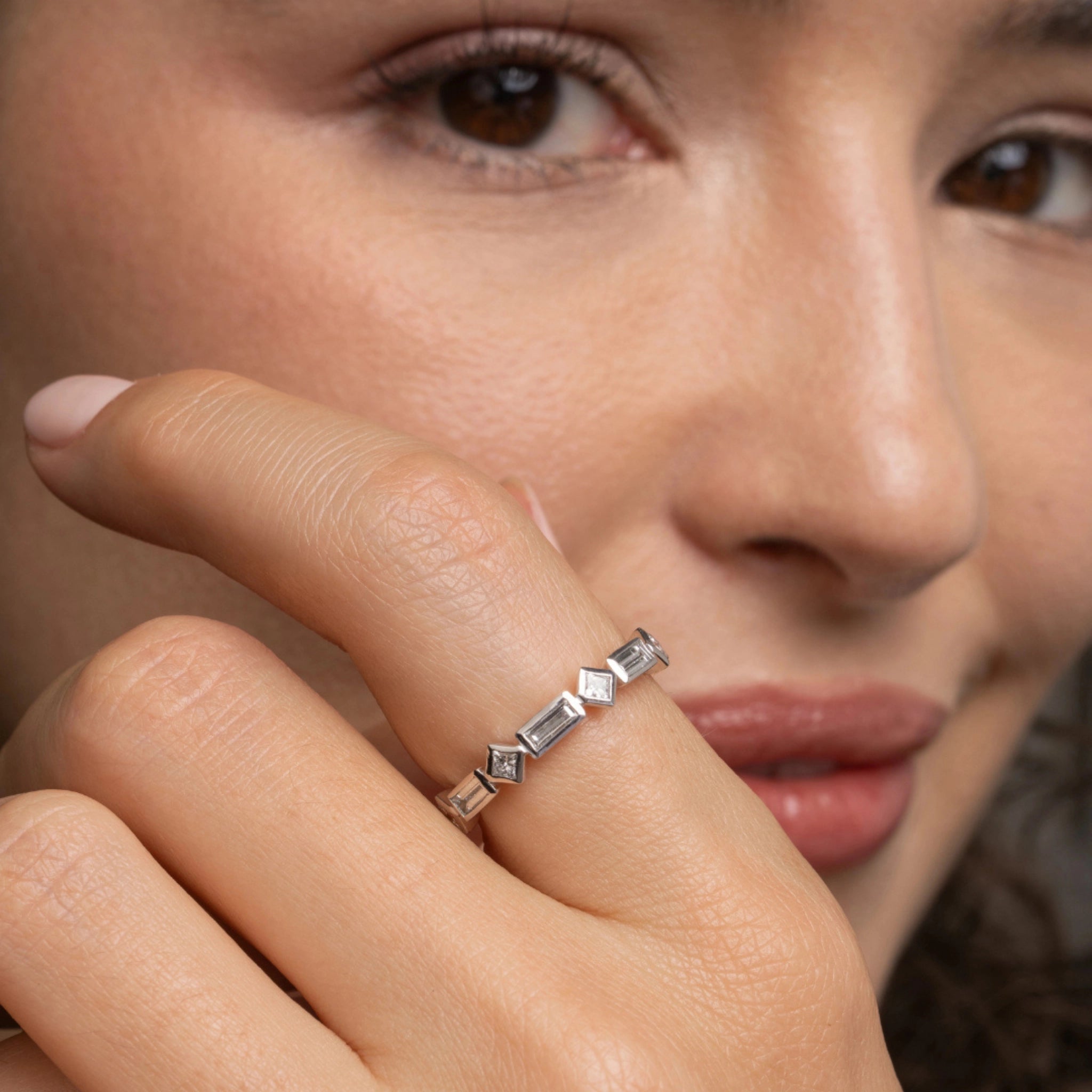 Elegant diamond ring featuring princess and baguette cut stones, worn on a model's hand, showcasing modern design.