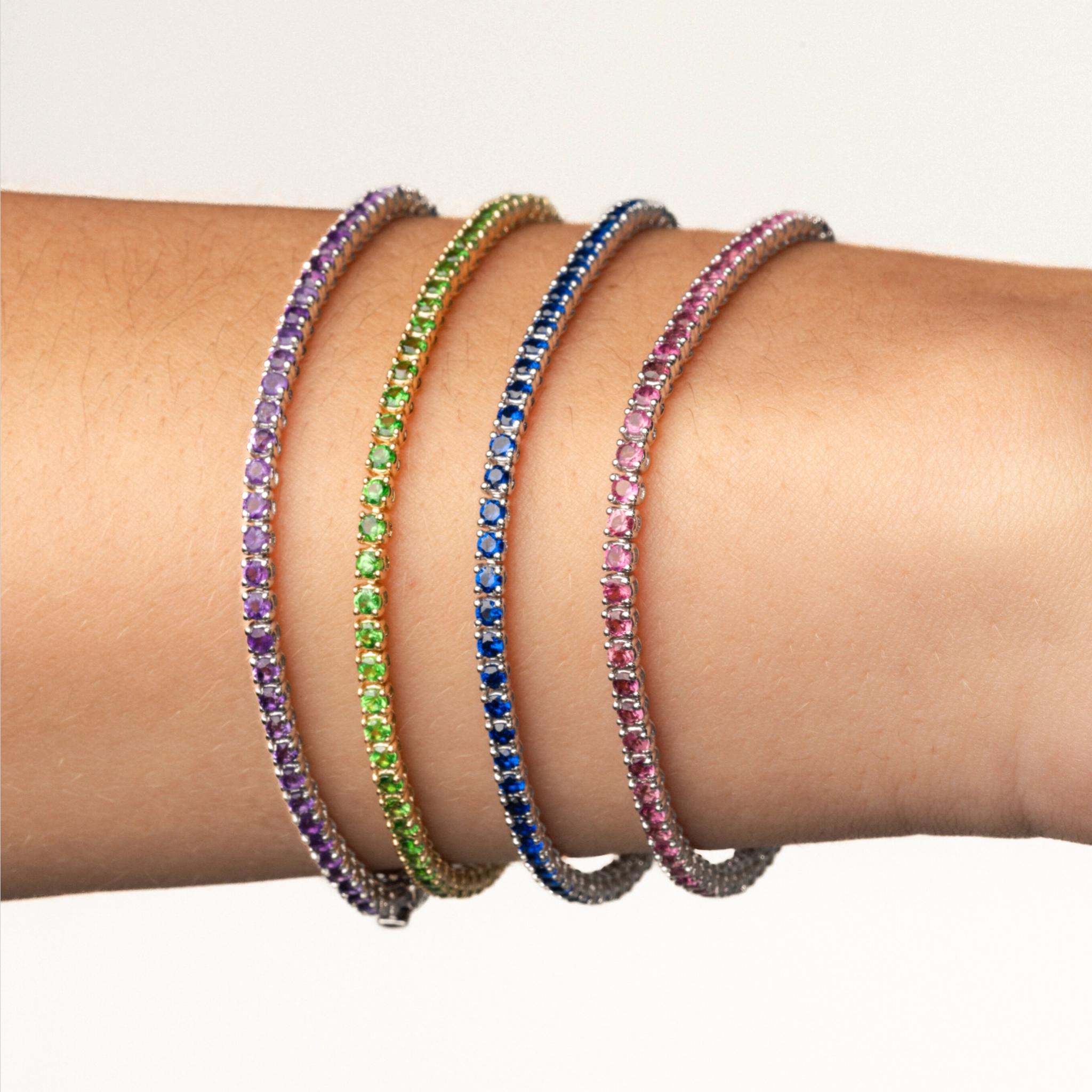 Colourful gemstone tennis bracelets displayed on a wrist showcasing elegance and luxury.