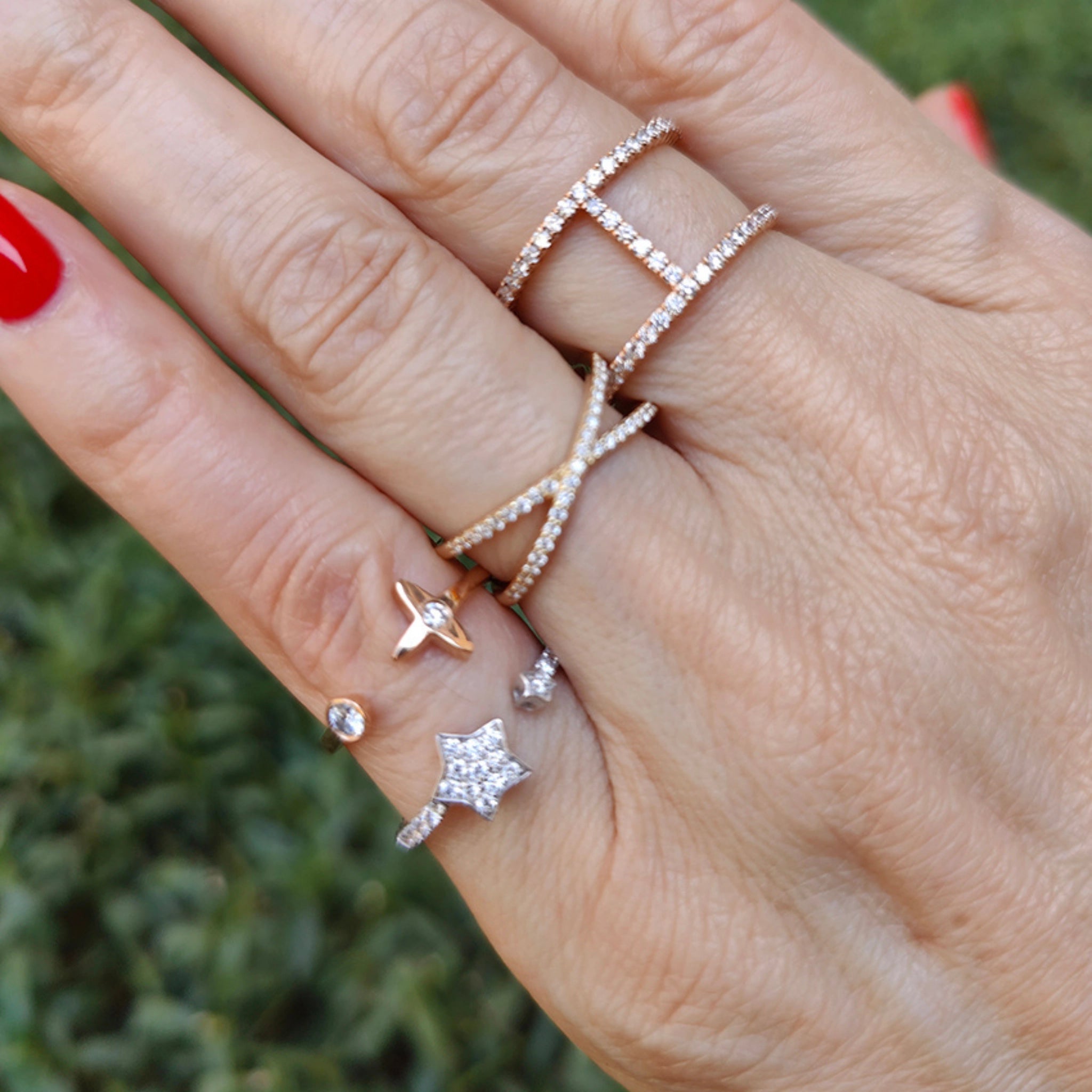 Hand adorned with multiple elegant diamond rings showcasing a star design and various styles in gold settings.