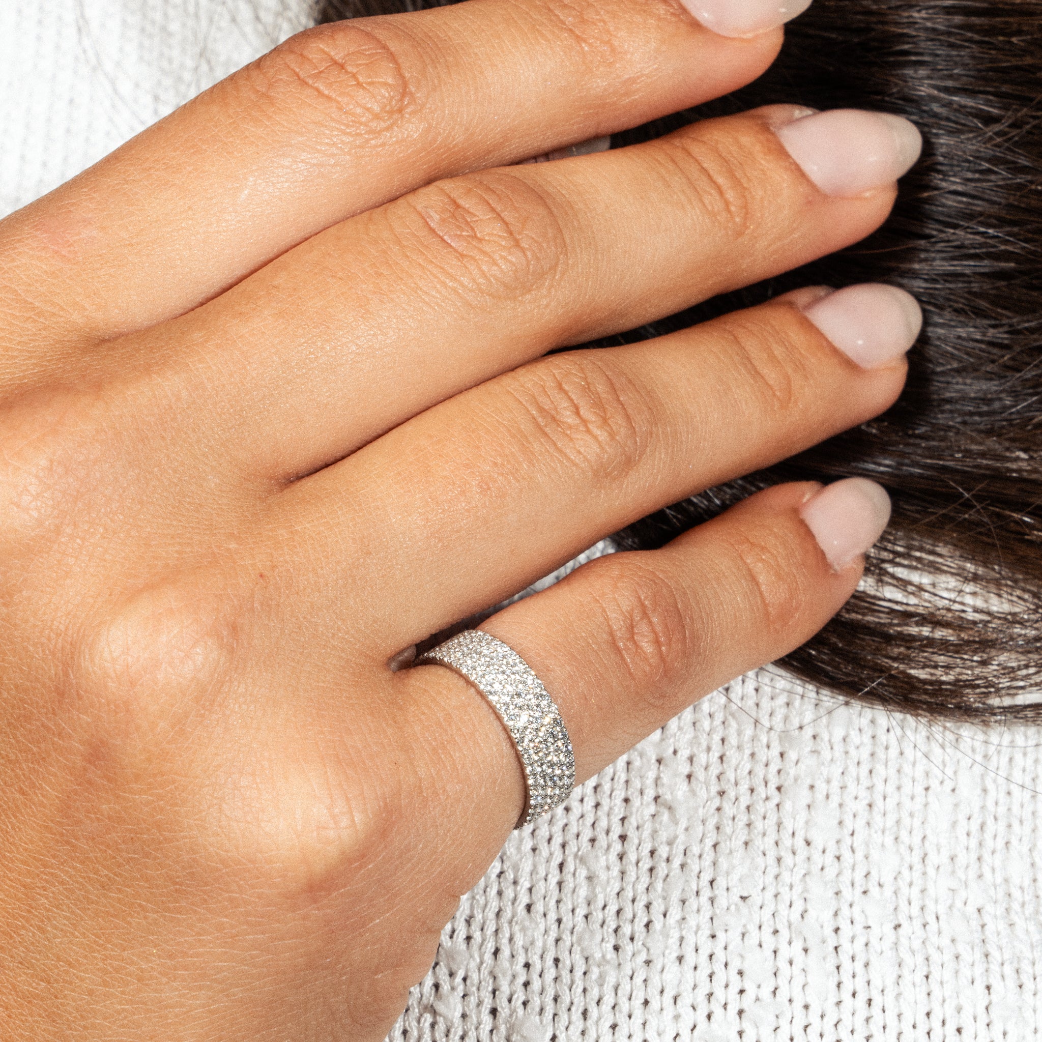 Five row pavé diamond ring on a hand, showcasing round brilliant cut diamonds in modern luxury design.