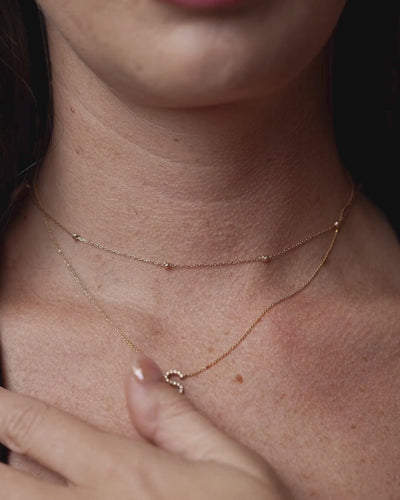 Woman wearing single diamond necklace with certified diamonds featuring a sparkling letter S pendant in gold.