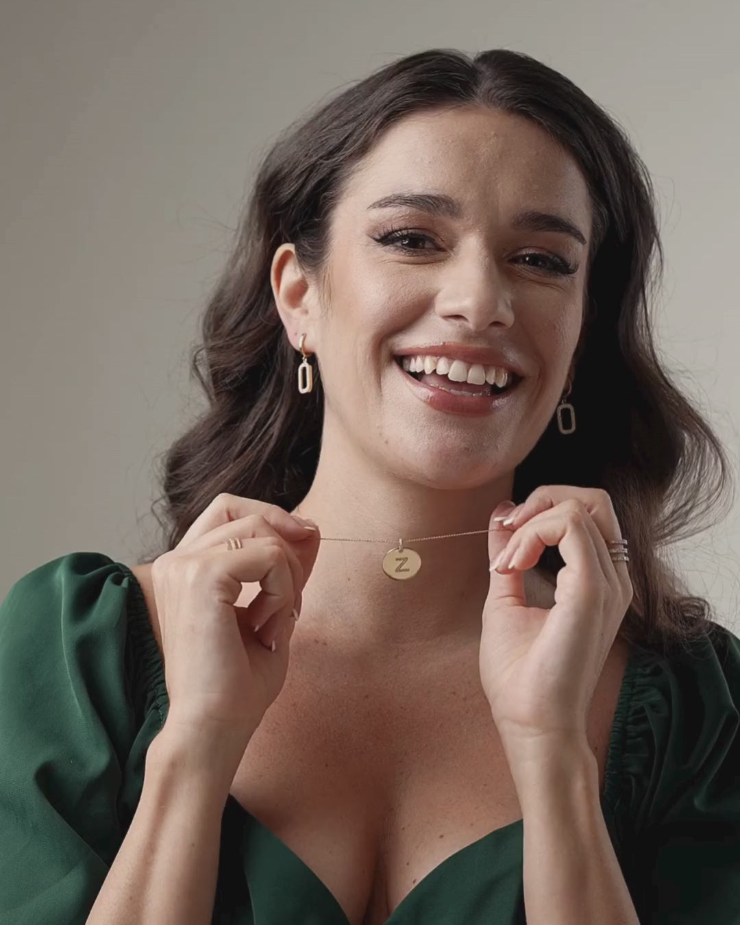 Woman smiles while holding a certified diamond necklace featuring a personalised disk pendant.