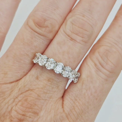 Seven stone oval certified diamond eternity ring showcasing exceptional craftsmanship and detail worn on a hand.