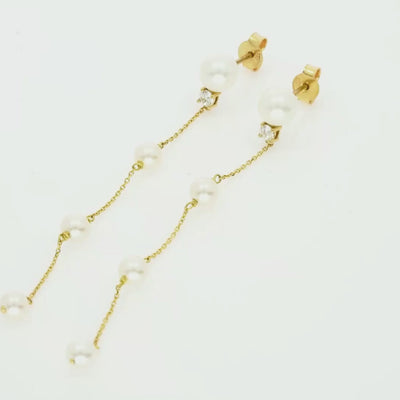 Long pearl drop earring with a single diamond set in 18ct yellow gold.