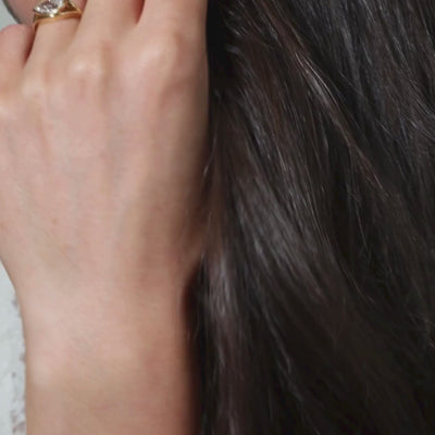 Close-up of a hand wearing a stunning Pear Shaped Ring in sculptural yellow gold, showcasing diamond brilliance.