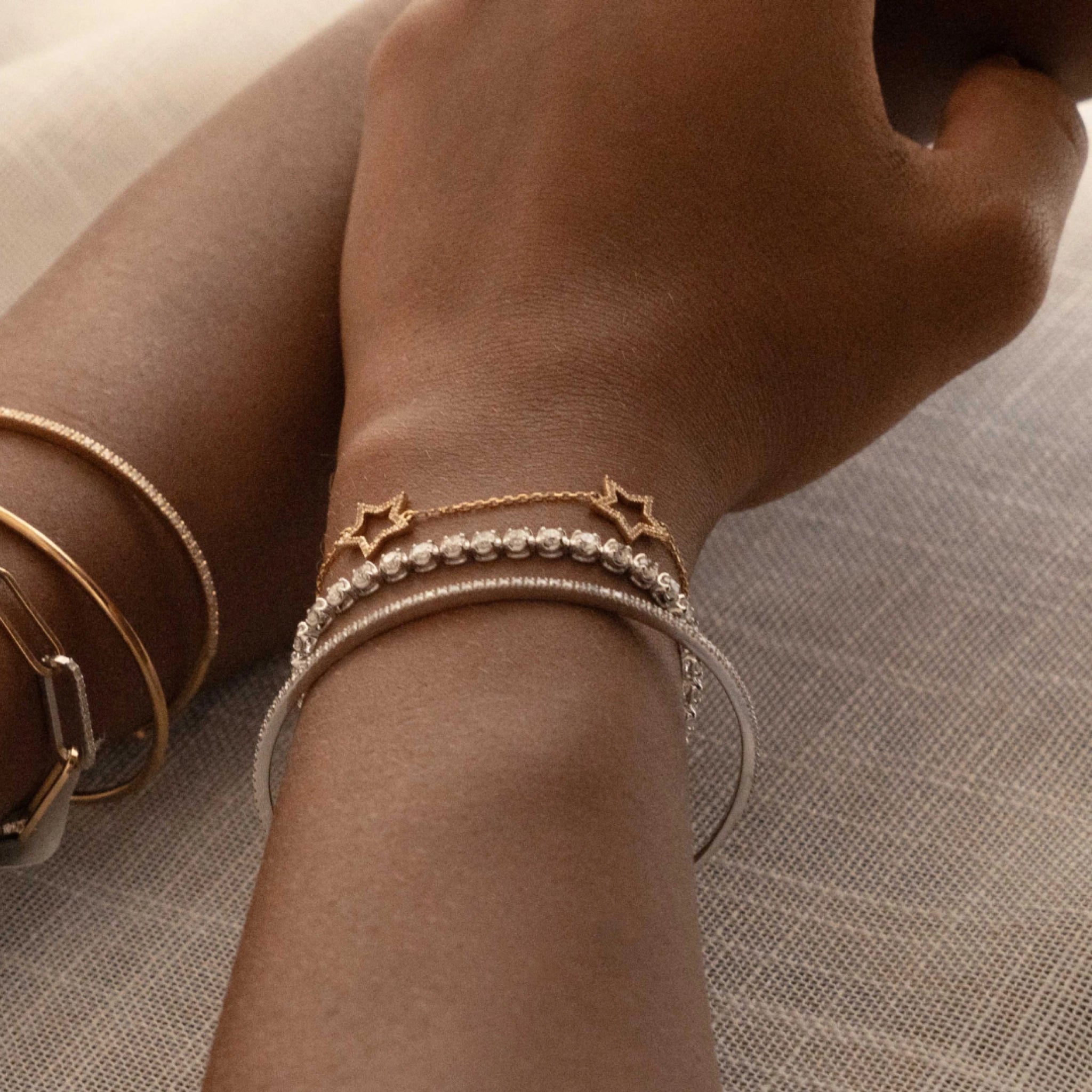 Close-up of a wrist adorned with modern bangles including a tennis bangle with diamonds.