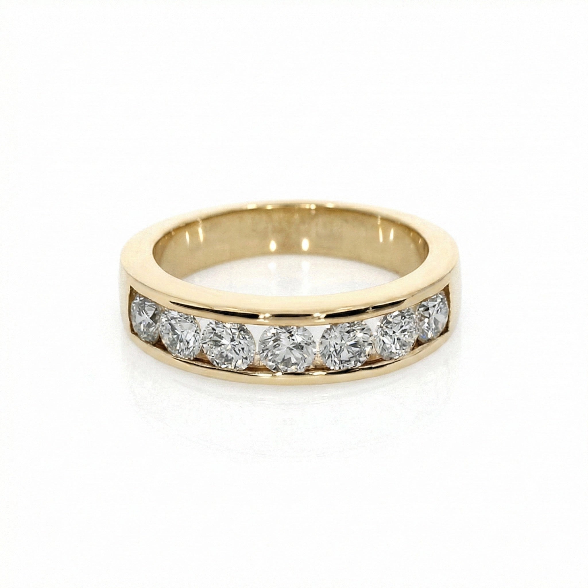 Round channel set diamond ring in yellow gold featuring seven brilliant cut diamonds in a modern gold band.
