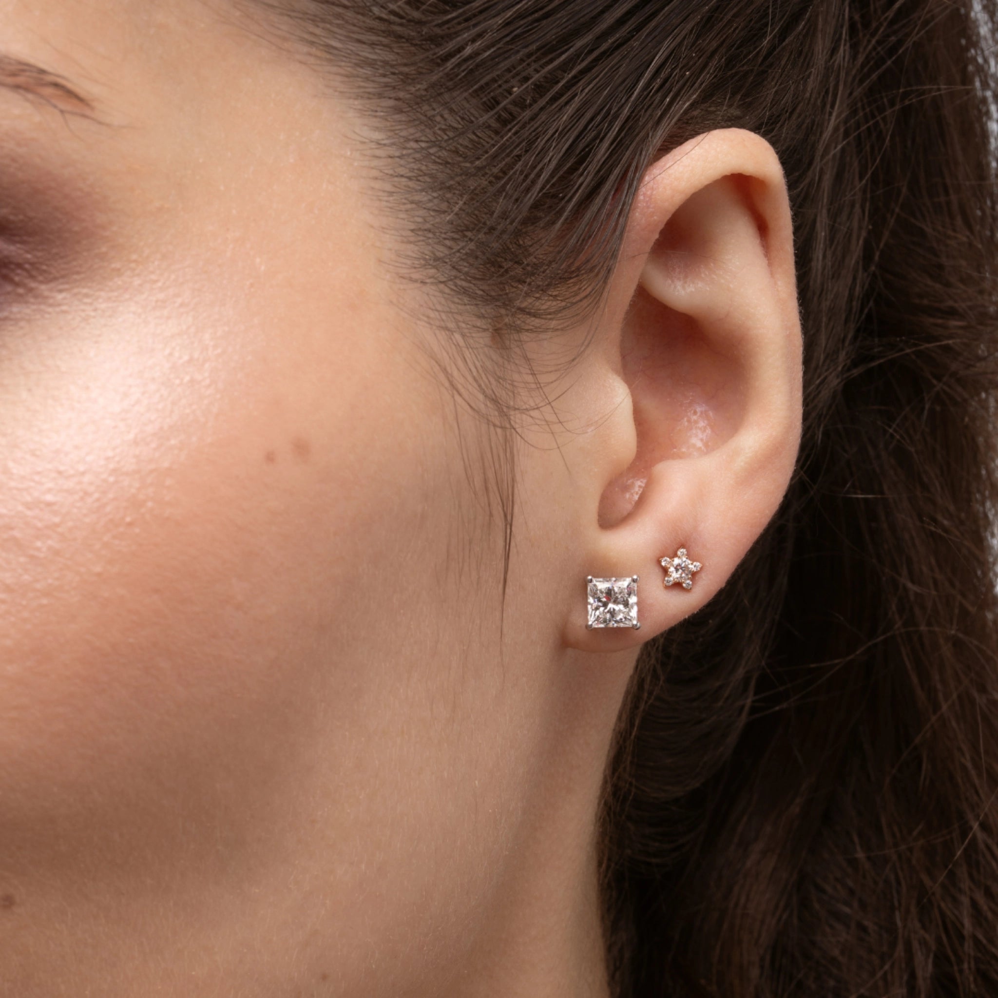 Small star earrings set with certified diamonds showcased on a model's ear, highlighting their elegant sparkle.
